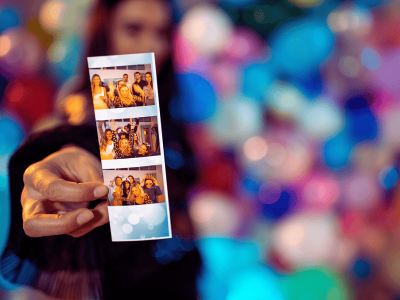 Printed photo booth strips featuring guests with fun props and backgrounds, used as keepsake favors for a baby shower.