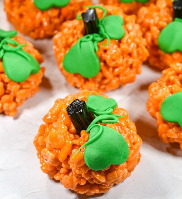 Pumpkin-shaped Rice Krispie treats decorated with fondant leaves and licorice stems—fun for kids to help make and perfect for Halloween.