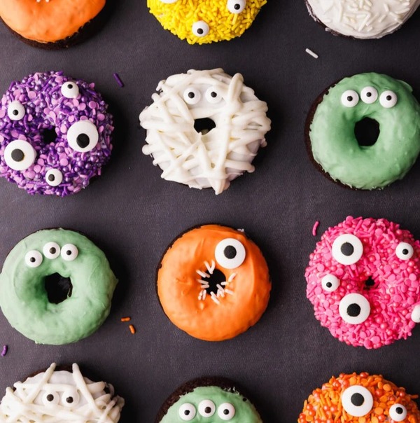 Halloween monster chocolate donuts made in a donut mold with candy eyeballs and colorful sprinkles.