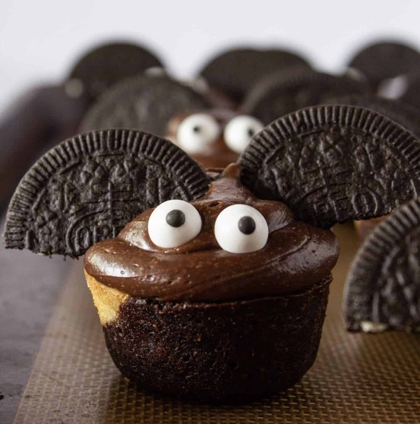 Halloween brownie bat bites made with brownie pieces, sandwich cookie wings, chocolate frosting, and candy eyes for a cute spooky after school treat.