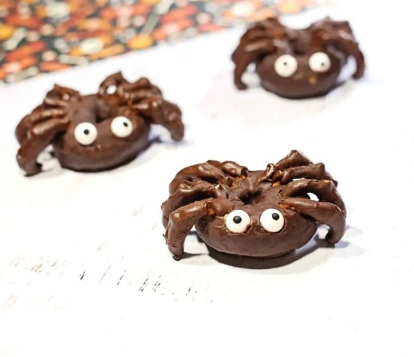 Mini donuts transformed into spider snacks with chocolate-dipped pretzel legs and candy eyes for a quick no-bake Halloween treat.
