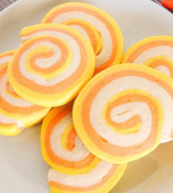 Candy corn pinwheel cookies made with swirled sugar cookie dough tinted in yellow, orange, and white for an easy Halloween cookie kids will love.