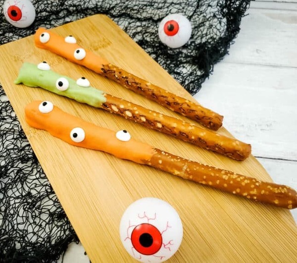 Halloween monster pretzel rods dipped in colorful candy melts and decorated with candy eyeballs for a salty and sweet spooky treat.