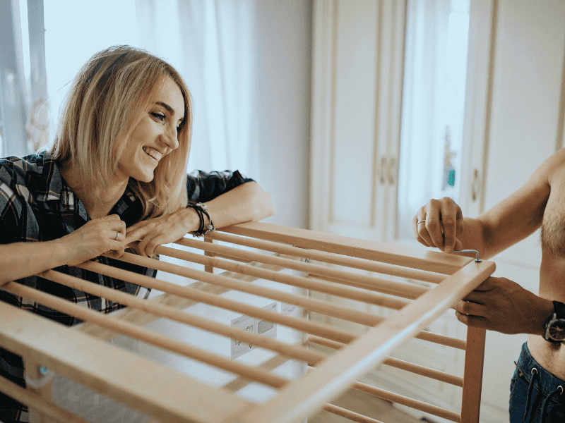 Woman setting up a baby crib for a nesting party baby shower.