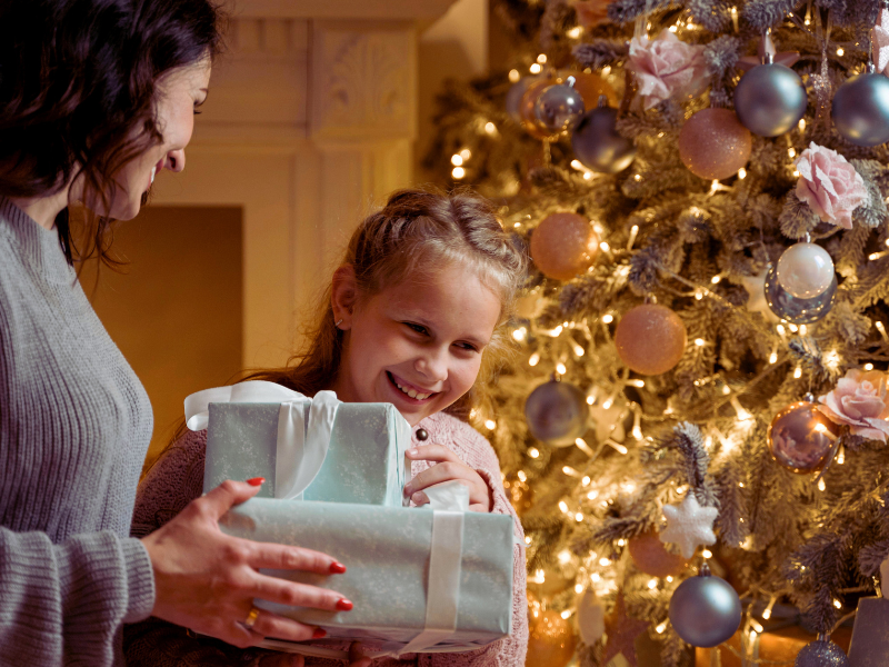 Child giving Christmas gift to parent first is a great Christmas morning tradition for families