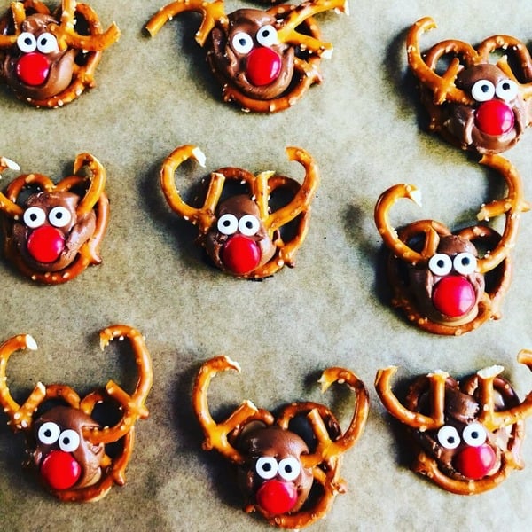 Reindeer pretzel treats made with chocolate candies, candy eyes, and pretzel twists for an easy Christmas snack.