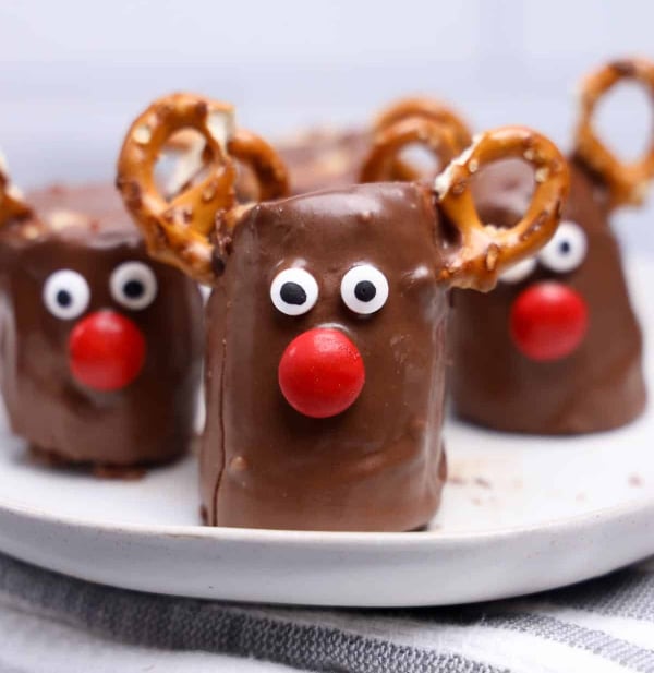 Rudolph chocolate-covered banana bites decorated with mini pretzel antlers, candy eyes, and red candy noses, an easy no-bake Christmas snack for kids.