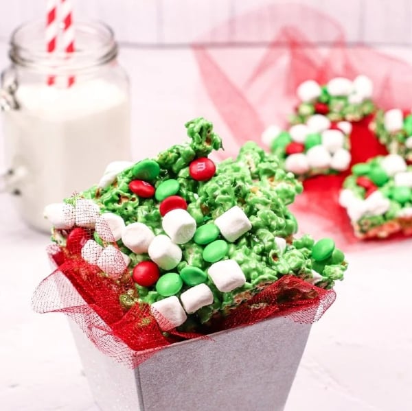 Grinch popcorn made with green candy-coated popcorn, red heart sprinkles, and candies, an easy no-bake Christmas snack mix for kids.