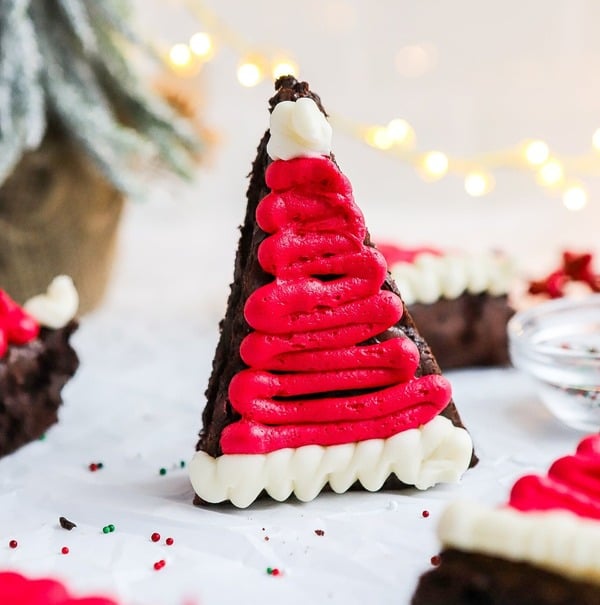 Gluten-free Santa hat brownies topped with red and white frosting shaped like Santa hats, an easy Christmas dessert for kids.