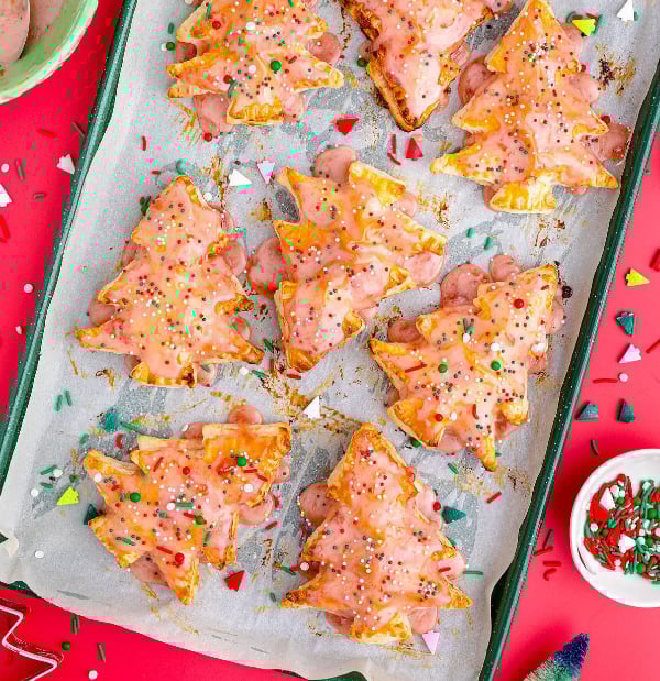 Homemade Christmas tree pop-tarts filled with jam and topped with pink jam icing and sprinkles, an easy and festive holiday treat for kids.