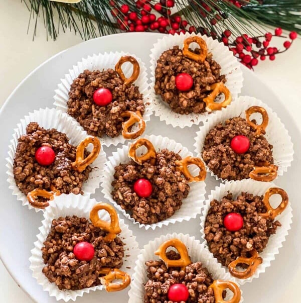 Chocolate reindeer crackles made with puffed rice cereal, coconut, melted chocolate, pretzel antlers, and red candy noses, an easy no-bake Christmas treat for kids.