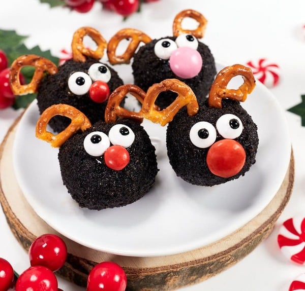 No-bake reindeer cookie balls made with crushed Oreo cookies, chocolate coating, pretzel antlers, and red candy noses, a fun Christmas treat for kids.