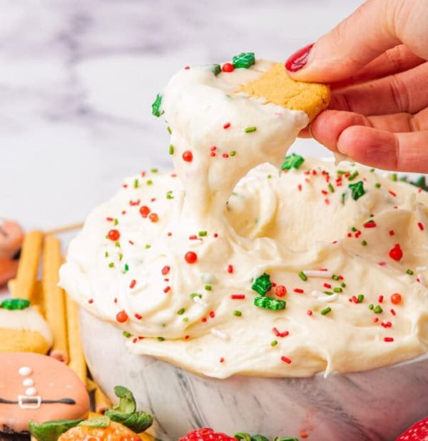 Christmas cookie dip topped with red and green sprinkles, served with graham crackers and pretzels, an easy no-bake holiday treat.