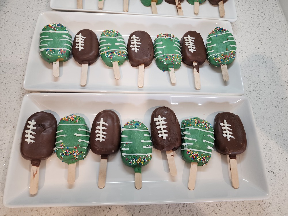 Cake pops decorated as footballs and football fields, arranged on a tray for a football-themed party.