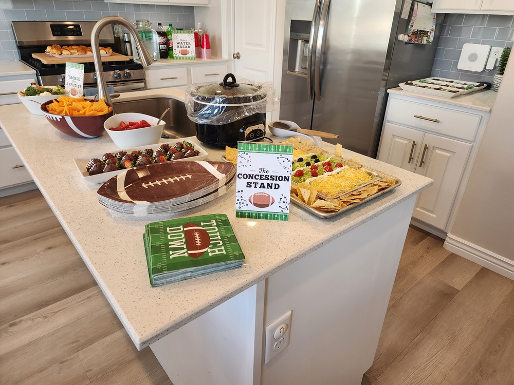 Football-themed party tableware laid out on a table, including plates, cups, napkins, and decorations matching the “First Year Down” birthday theme.
